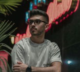 a man sitting in front of a neon sign
